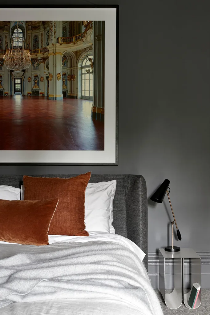 Grey bedroom with rust coloured cushions. Belle