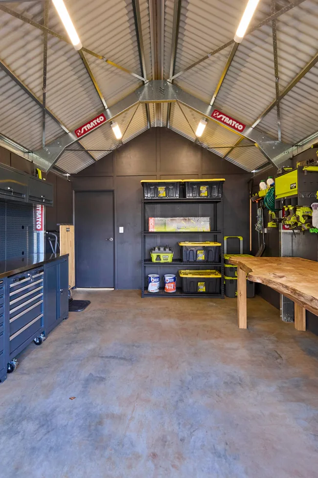A shed with a work bench, storage and hanging tools on The Block