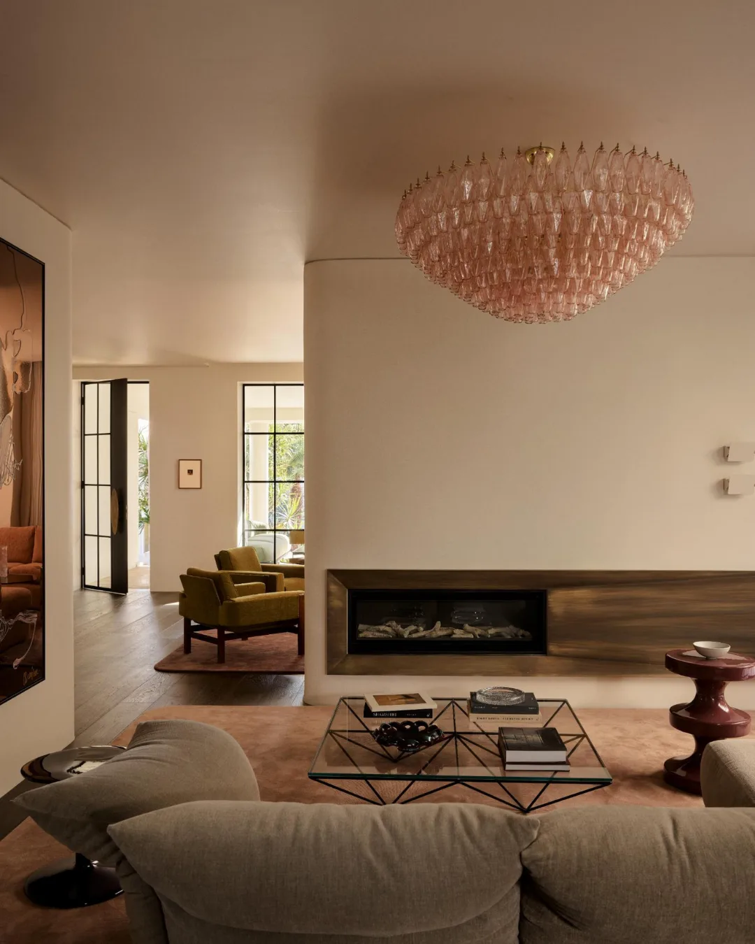 Contemporary living room with pink chandelier, geometric coffee table, and modern fireplace.