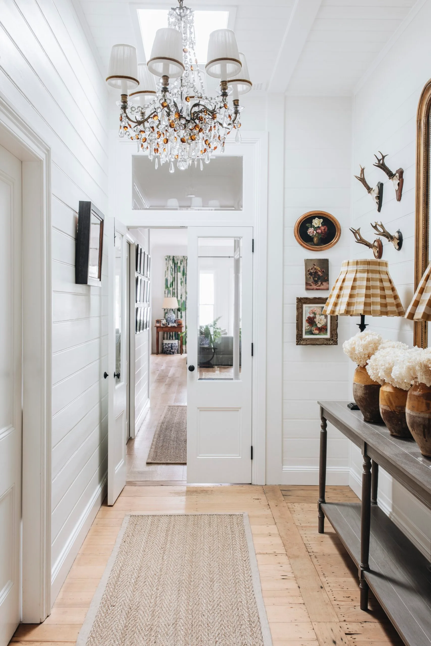 A hallway with a chandelier and white panelled walls