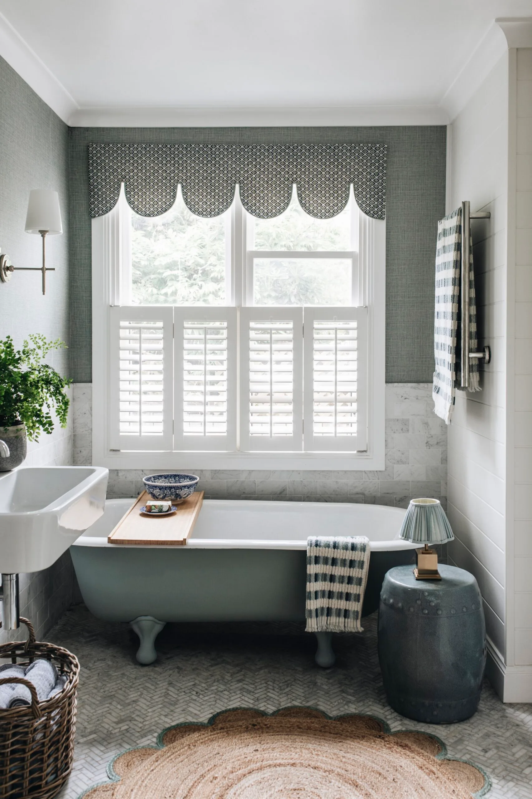 A bathroom with a clawfoot tub and round jute rug