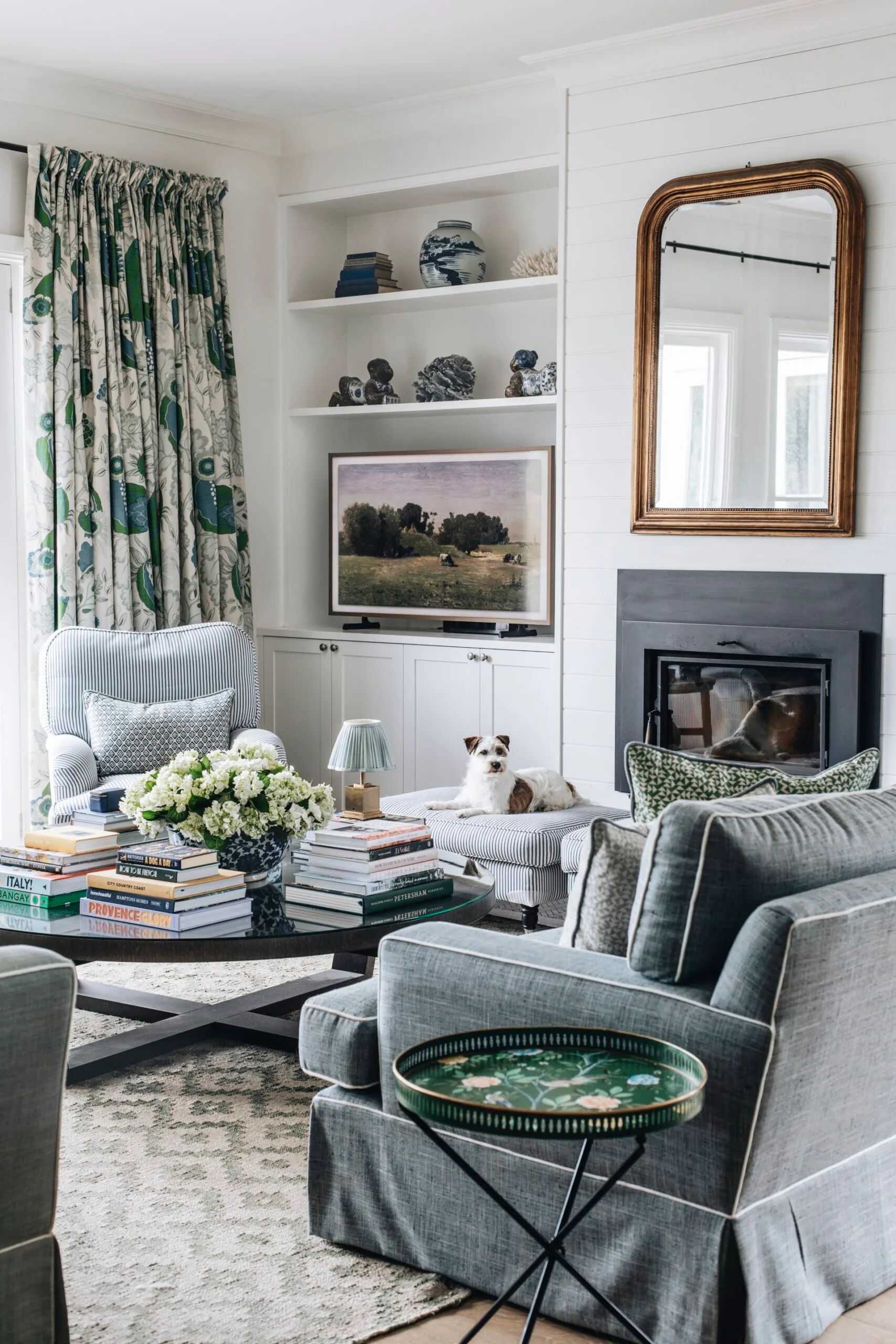A country living room with blue sofas and a dog resting on a foot rest