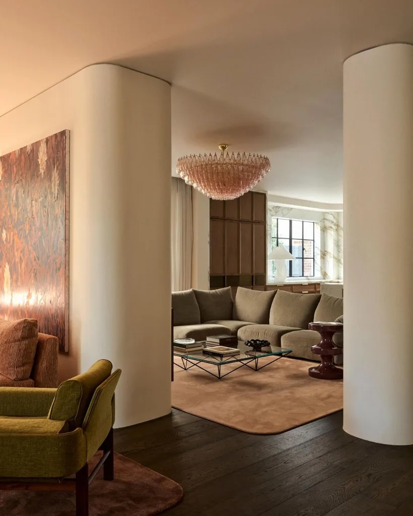 Glamourous living room with plush grey sofa, pink glass chandelier and curved white walls.