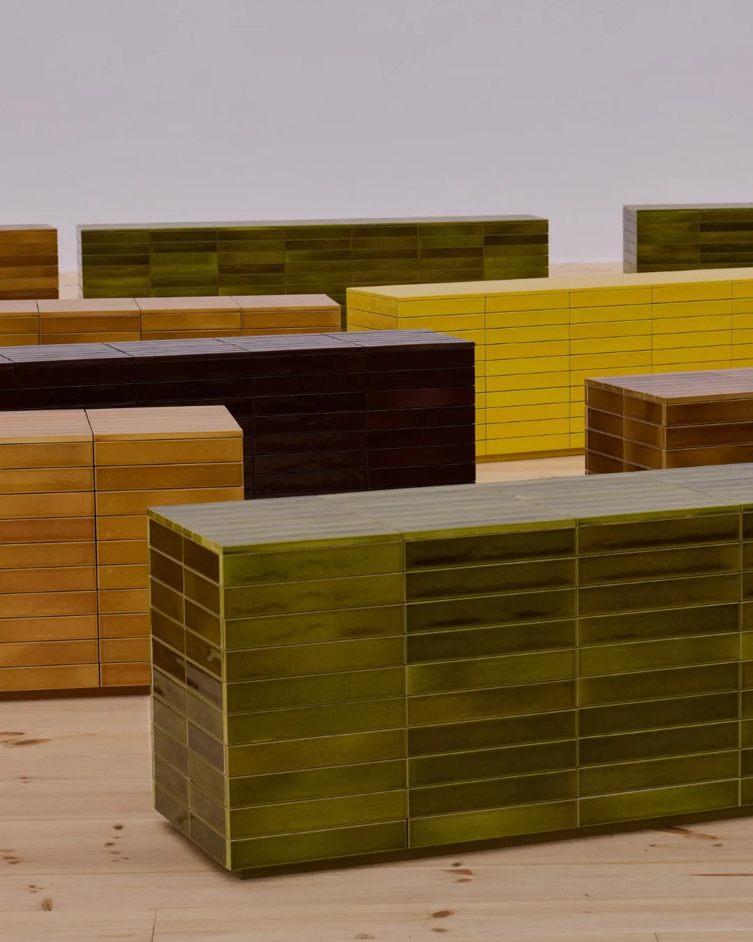 Sets of tiled seating in nature-inspired colours of deep green, caramel, black and yellow were set up for guests attending the Loewe Spring Summer 2026 show during Paris Fashion Week. 