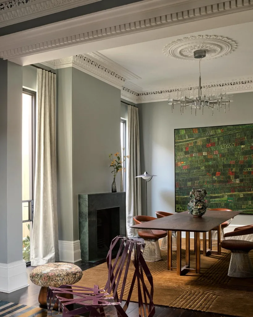 Elegant dining room with modern furniture, large abstract painting, intricate ceiling moldings, and abundant natural light.