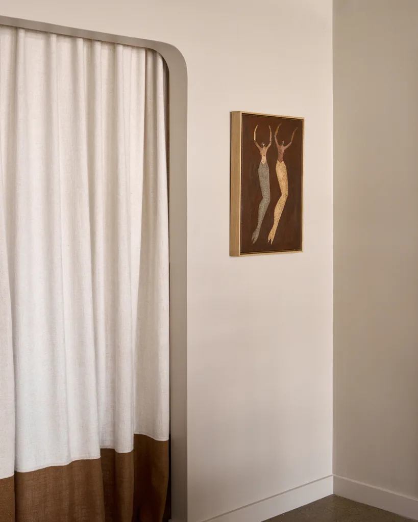 White walls with arched door frame with mustard and cream linen curtains and natural colours, abstract artwork.