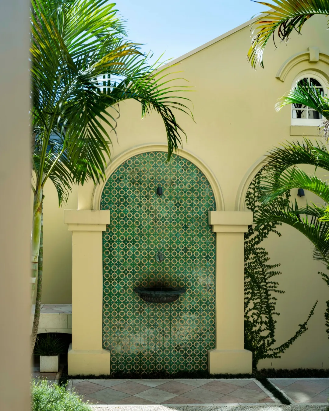 Arched water feature with jade tiles on the back wall of a small Moroccan style inner Sydney garden. 
