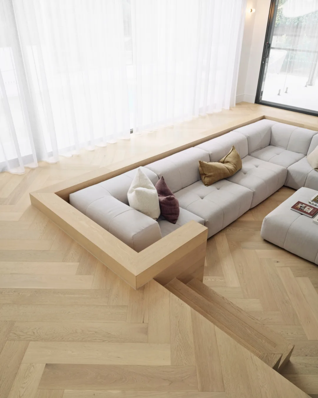 Sunken sitting area clad in herringbone laid engineered timber flooring. 
