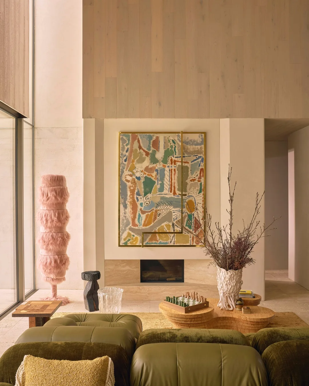 Modern lounge room with asymmetric walls, green leather couch, contemporary pastel artwork and marble fireplace.