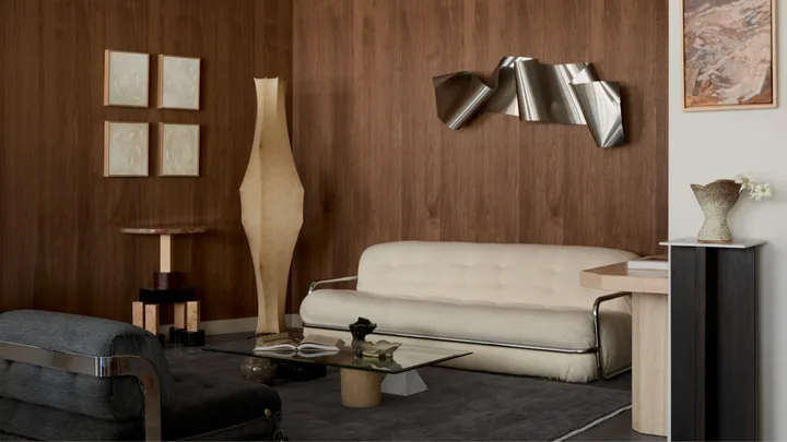 A wooden panelled room with white boucle couch, paper floor lantern and abstract metallic artwork hanging on the wall.