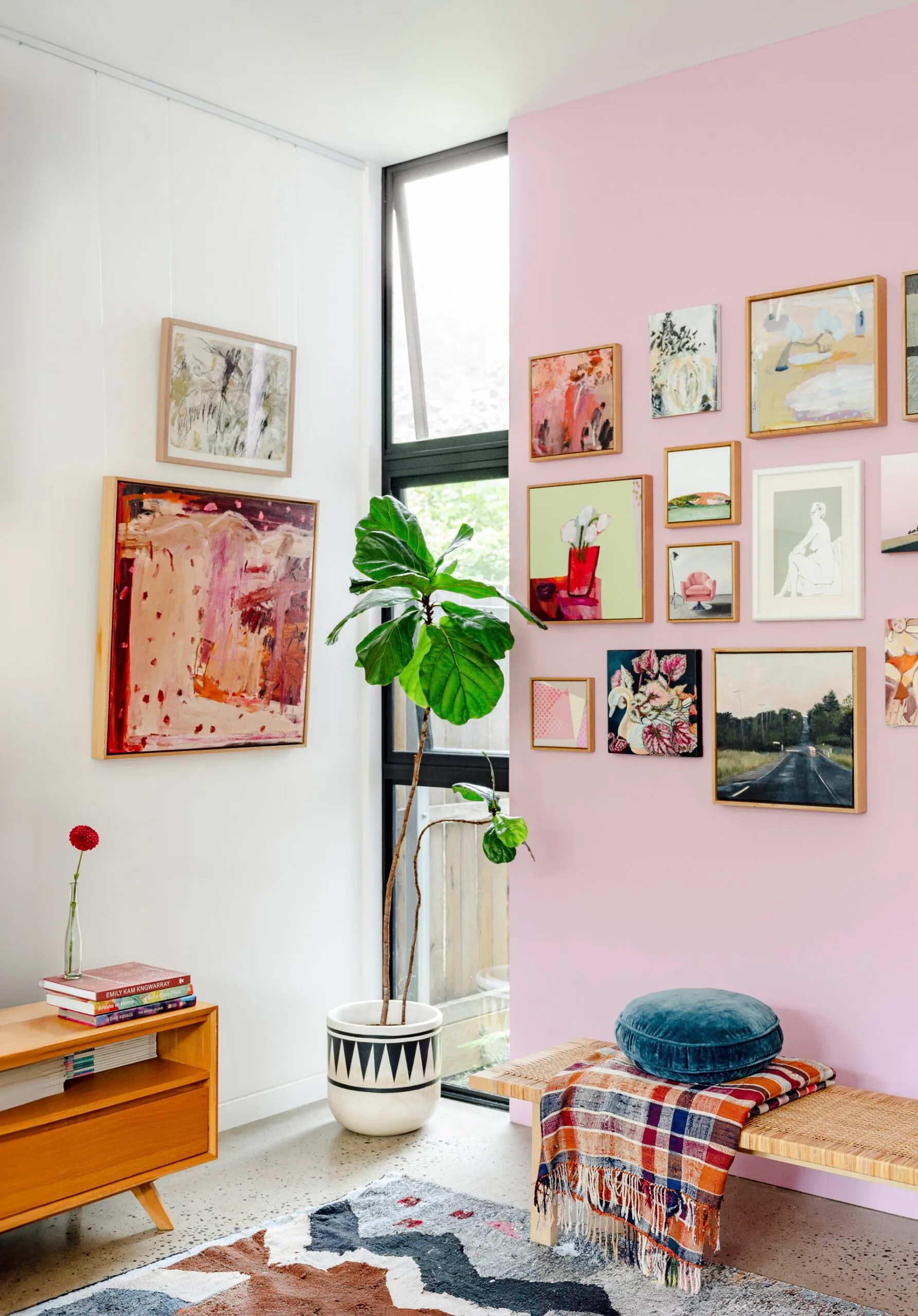 A pink wall with framed artworks hanging