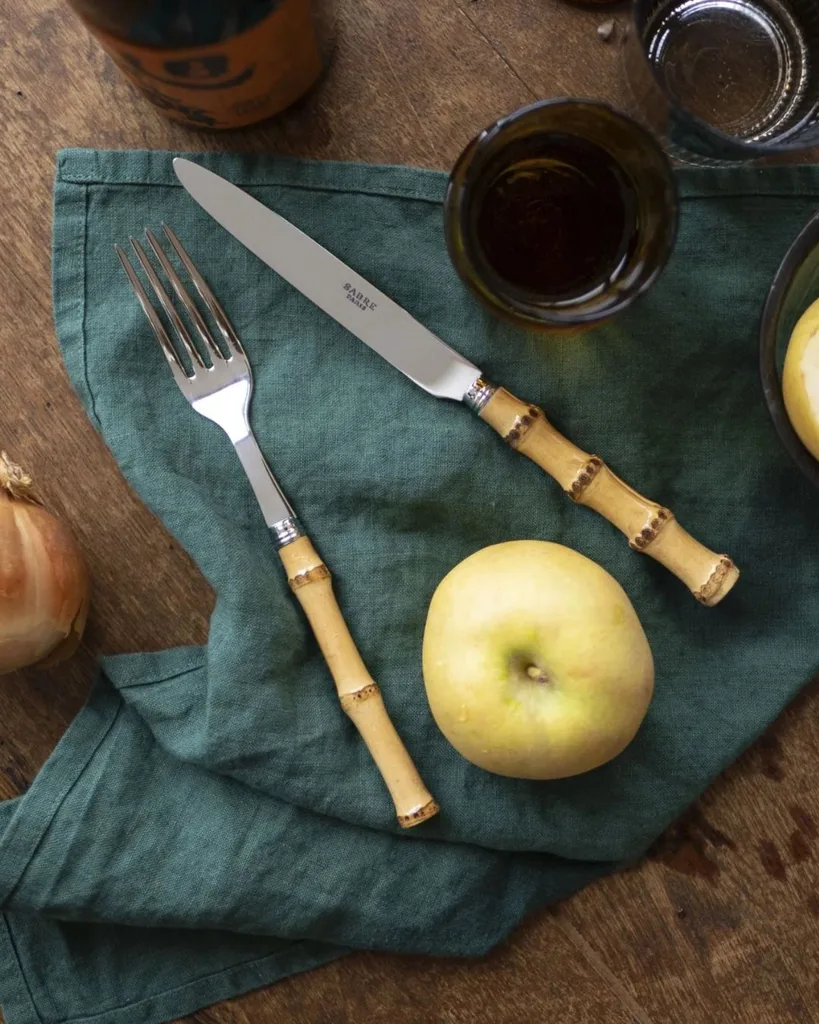 Sabre Paris bamboo handle cutlery on a forest green linen napkin.