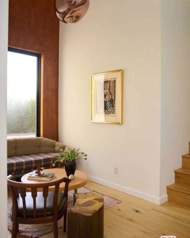 A pattern couch, timber chair, vintage artwork, timber round coffee table, window and stairs