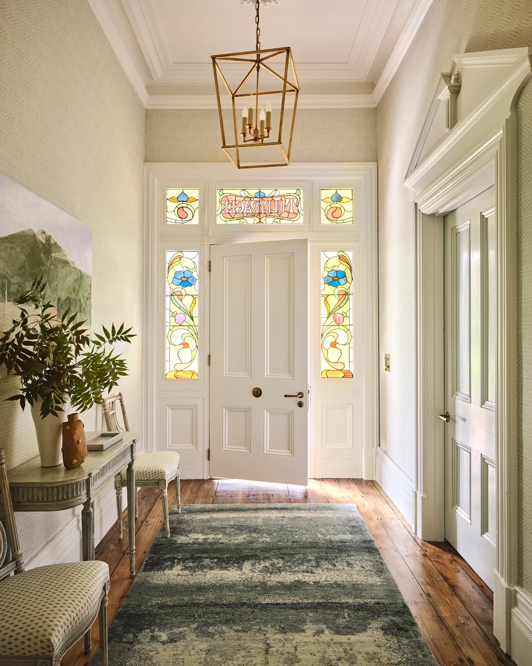 A white front door, green carpet, and stained glass mosaic