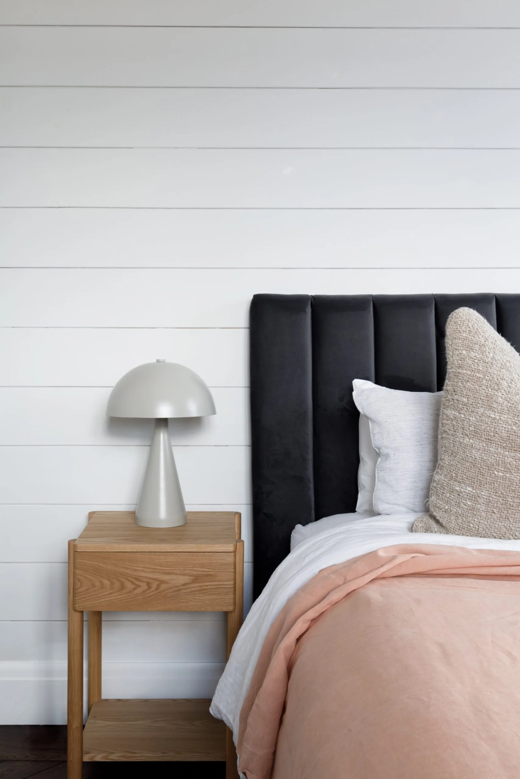 Bedroom with black bedhead, pink sheets and white walls