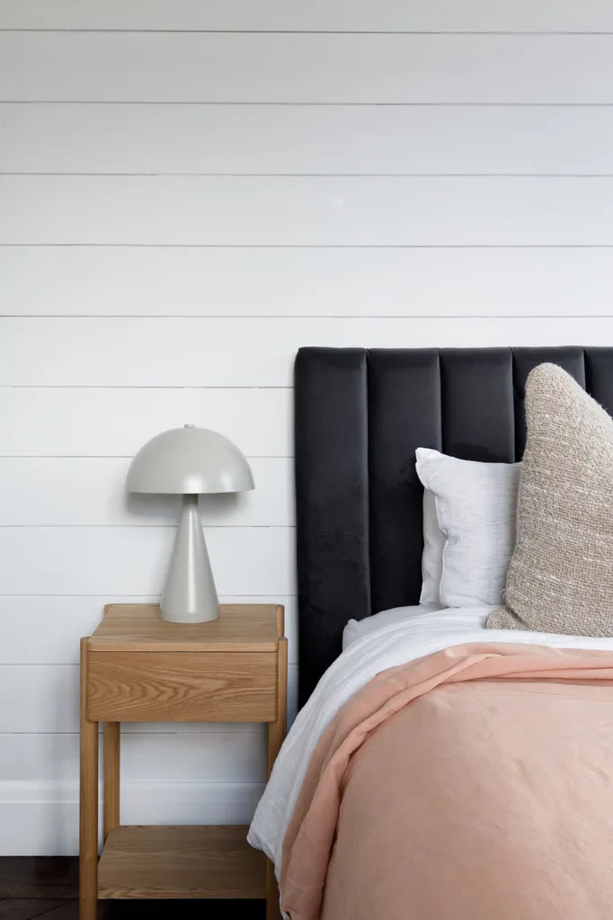 Bedroom with black bedhead, pink sheets and white walls