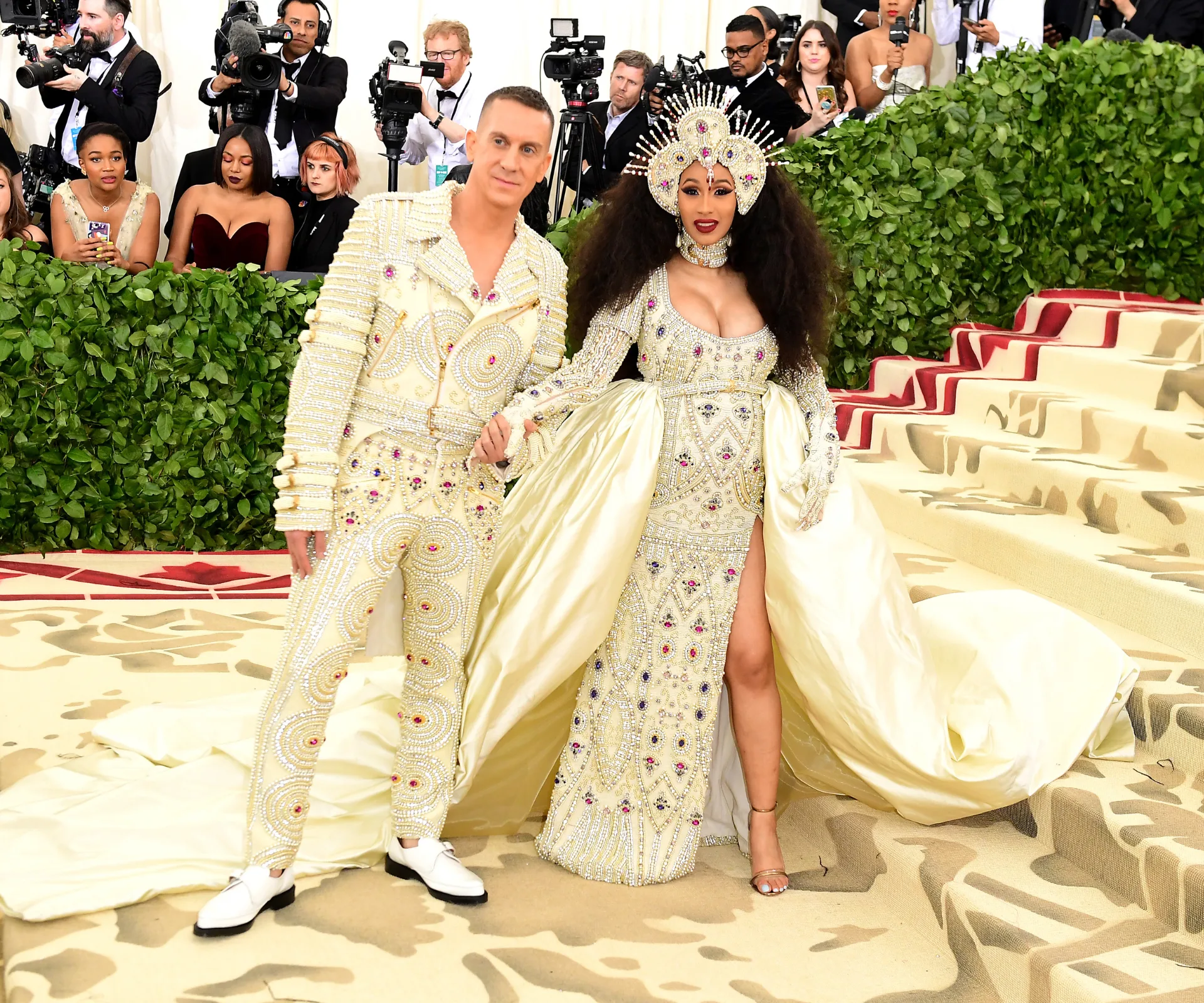 A woman and man posing in a gold dress on a gold carpet
