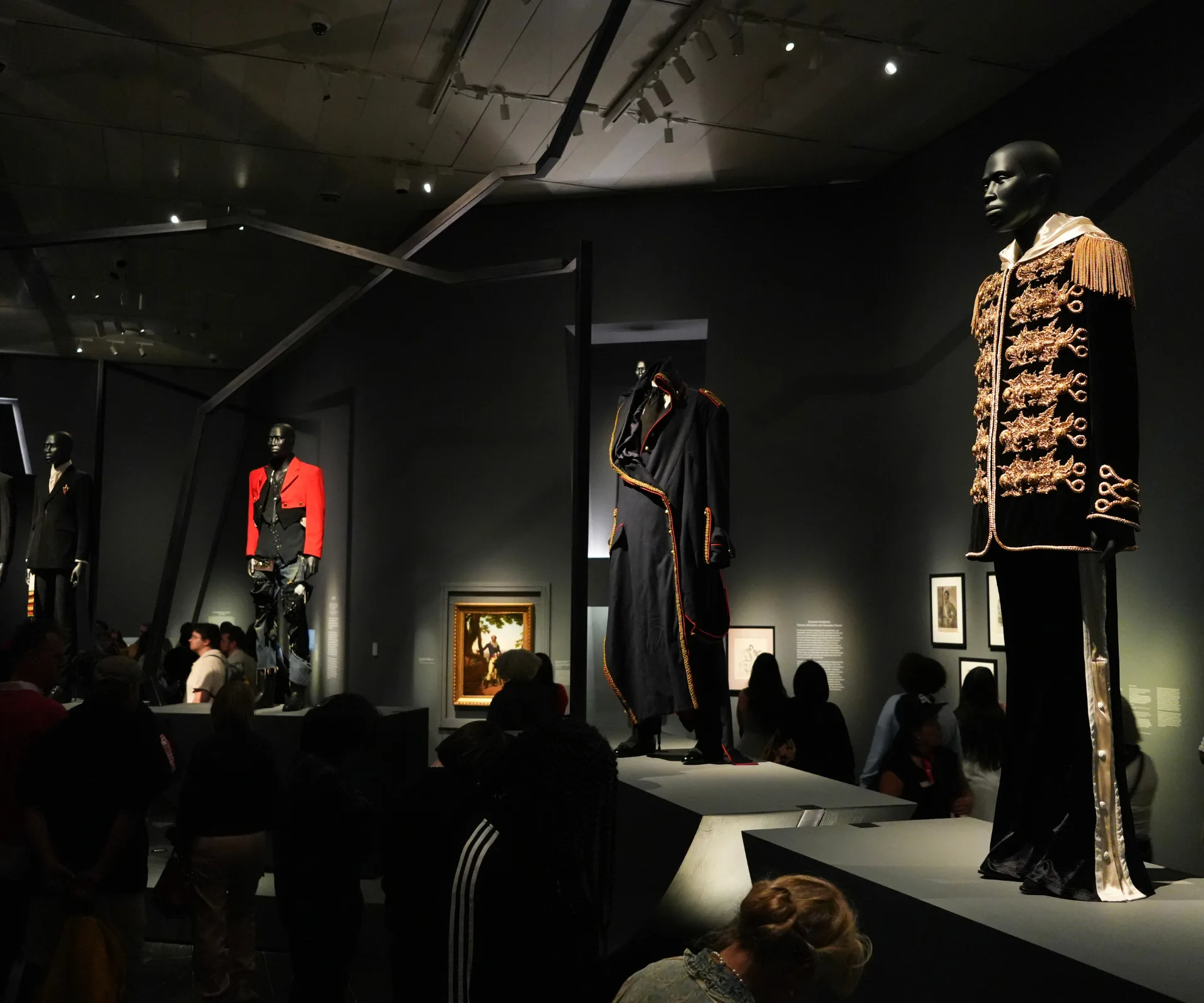 A black painted gallery with statues modelling costumes at the MET