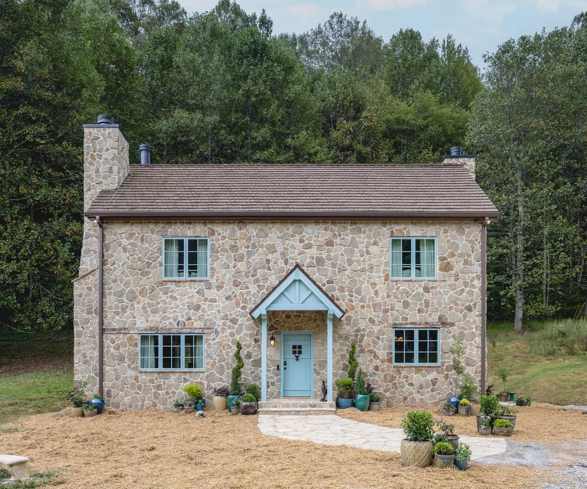 A brick-and-mortared cottage with blue framed windows and front door. 
