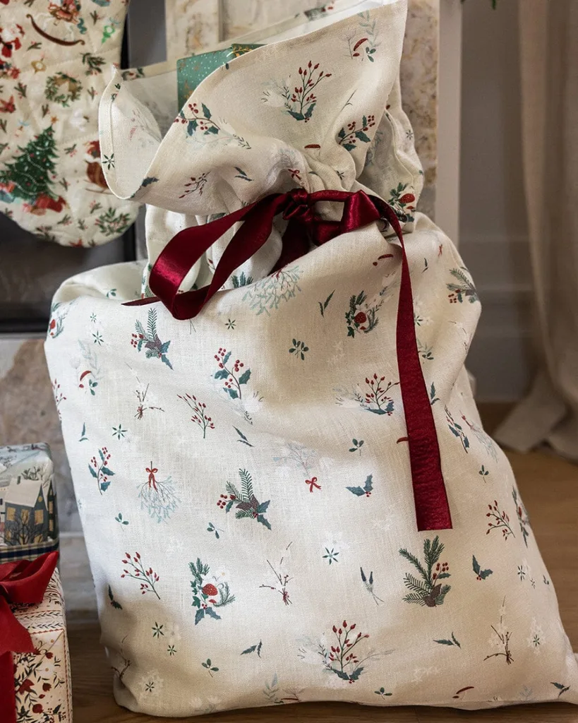 A stylish Christmas stocking with a big red bow. sitting next to beautifully wrapped presents on the floor.