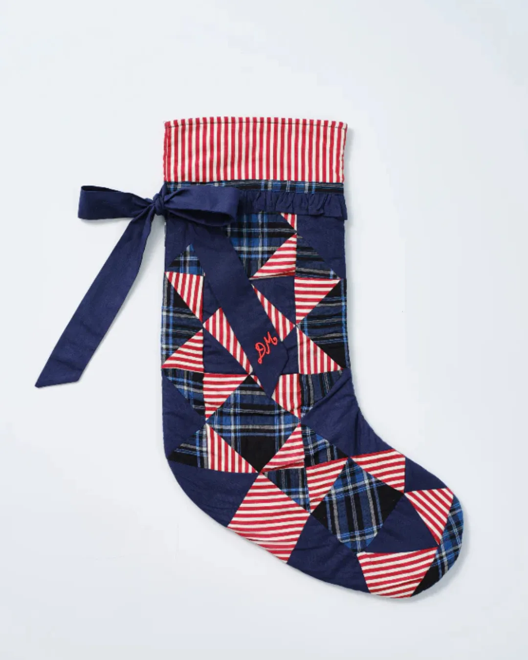 A Christmas stocking with red and white stipes, and navy ribbon and peplum.