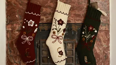 Three wool embroidered Christmas Stockings hanging on a marble fireplace