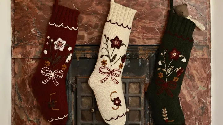 Three wool embroidered Christmas Stockings hanging on a marble fireplace