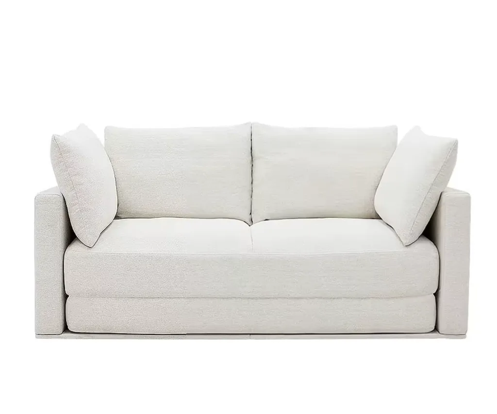 a white two seater couch with pillows placed on either end from