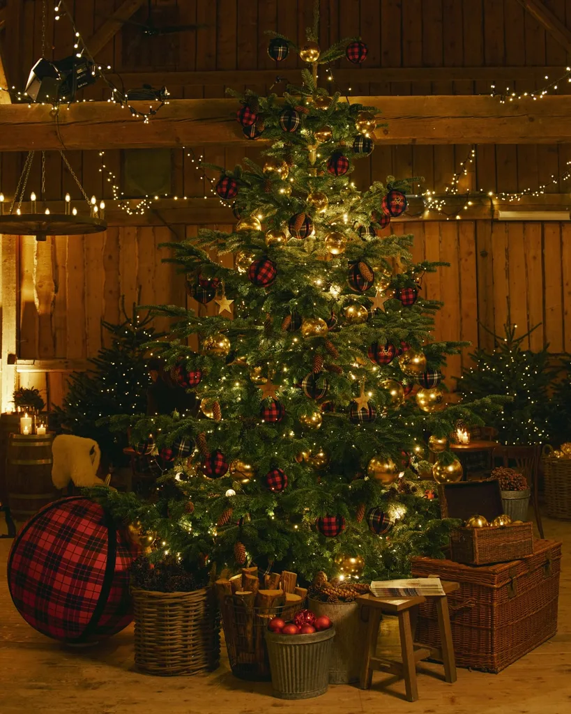 A decorate Christmas tree with a giant black and red tartan bauble on the floor from the Ralph Lauren Christmas campaign 2025 for Christmas Trends