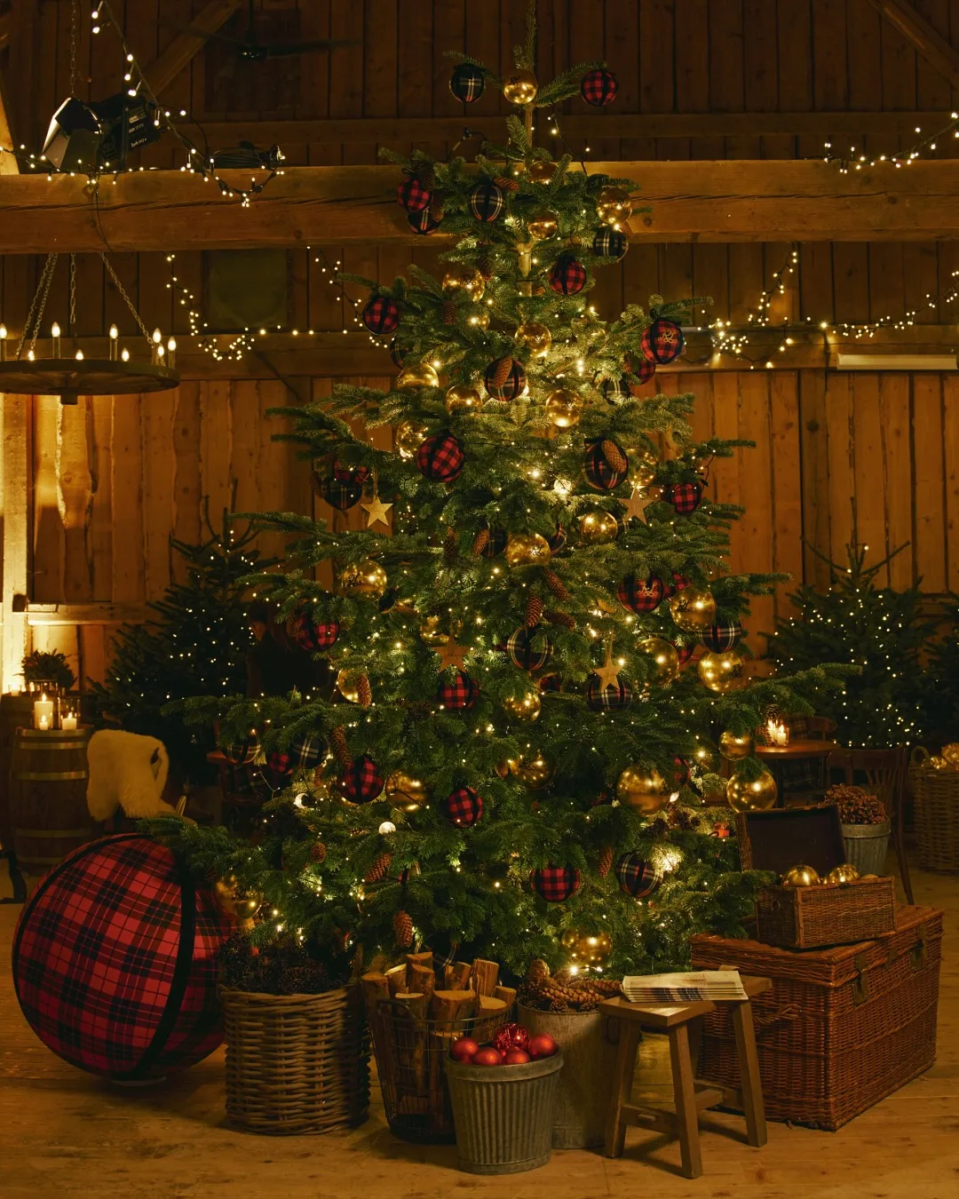 A decorate Christmas tree with a giant black and red tartan bauble on the floor from the Ralph Lauren Christmas campaign 2025 for Christmas Trends 