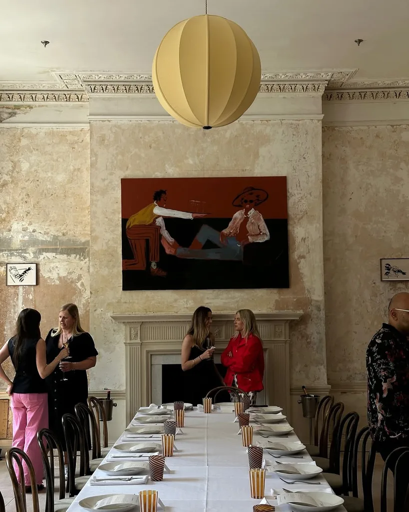 People standing around a dining table chatting, abstract artwork and paper lantern