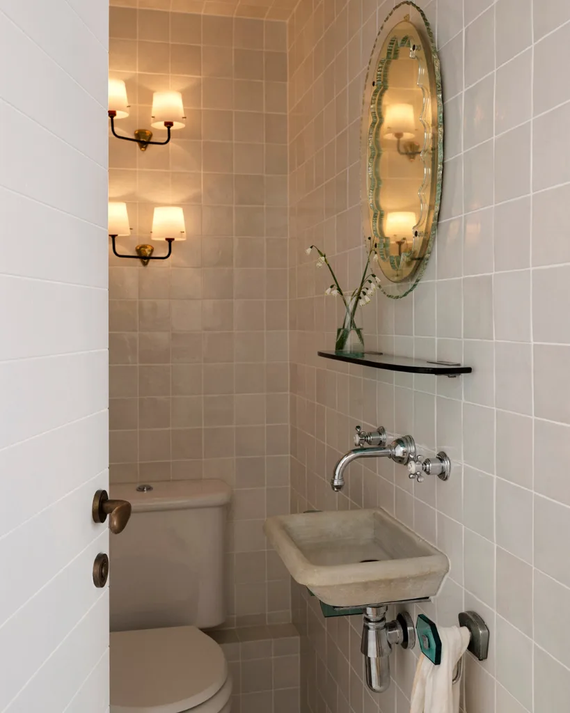 A powder room with soft lighting, abstract mirror, floating basin and silver tapware