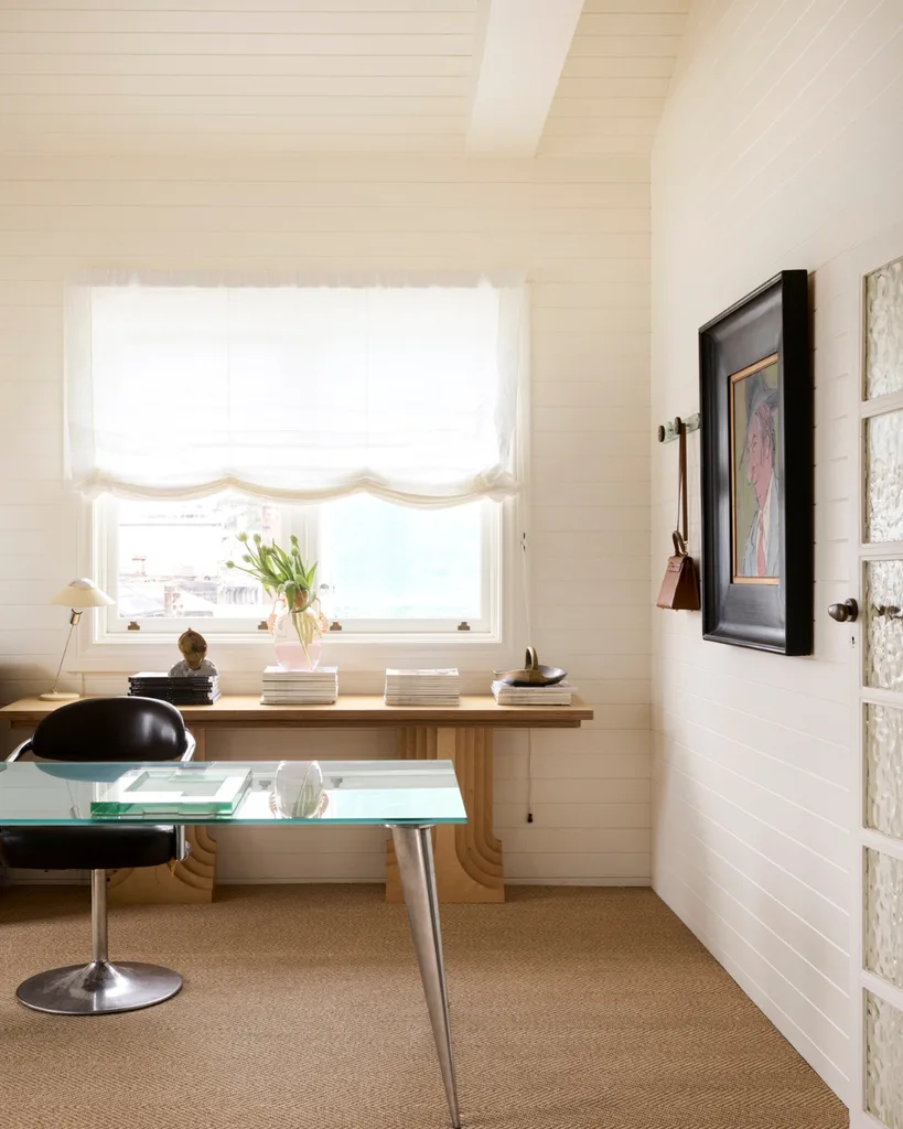A glass desk, black leather chair and historic artwork