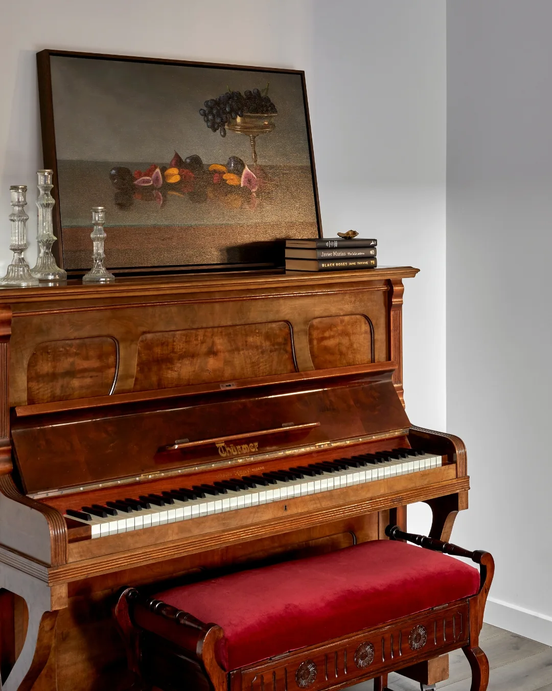 A still life artwork casually propped on top of an old walnut piano. 