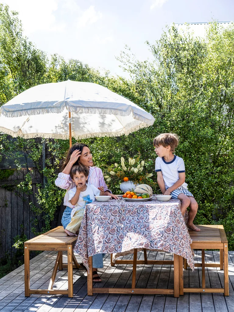 A family share a snack outside under an umbrella