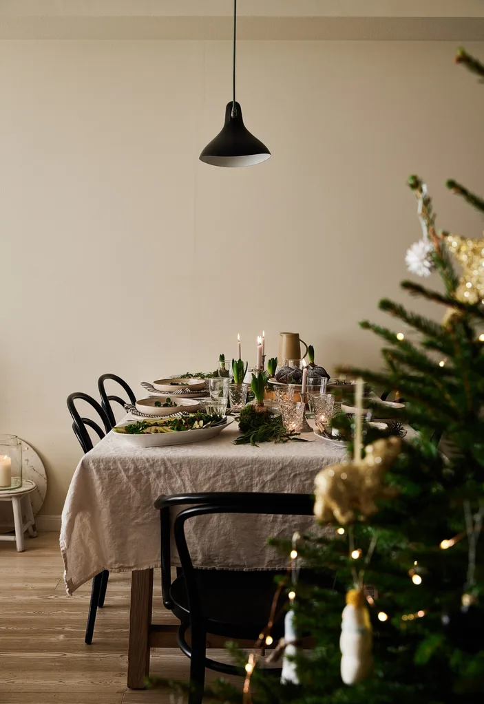 A Christmas tree beside a festively decorated dining table