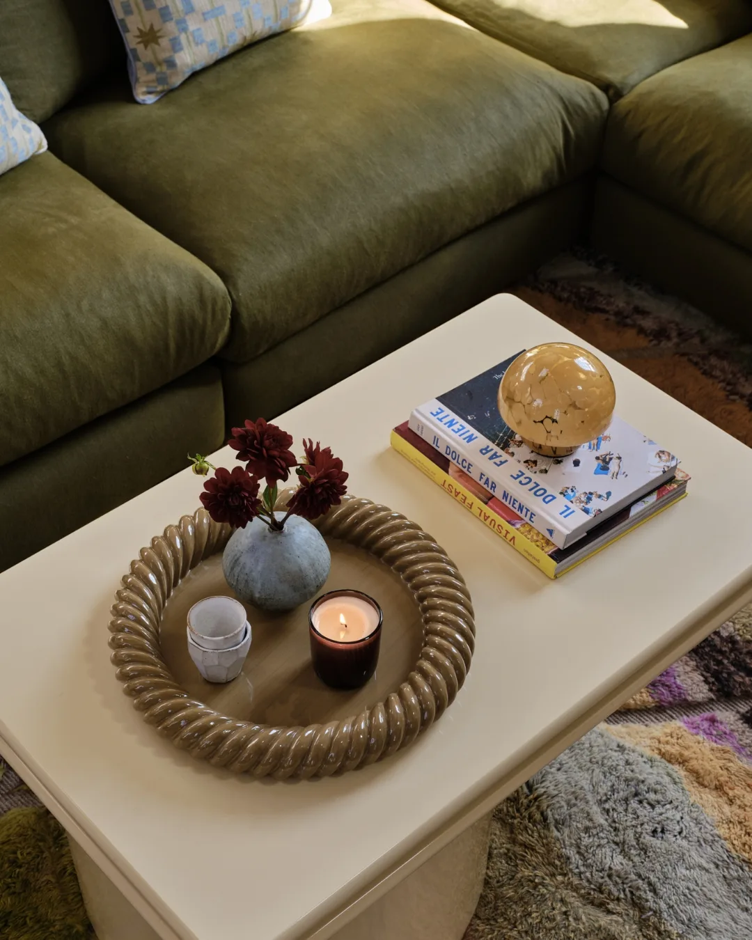 A close up of a cream coffee table with a round bowl, candles and books in the living room of Polly Sayer. 