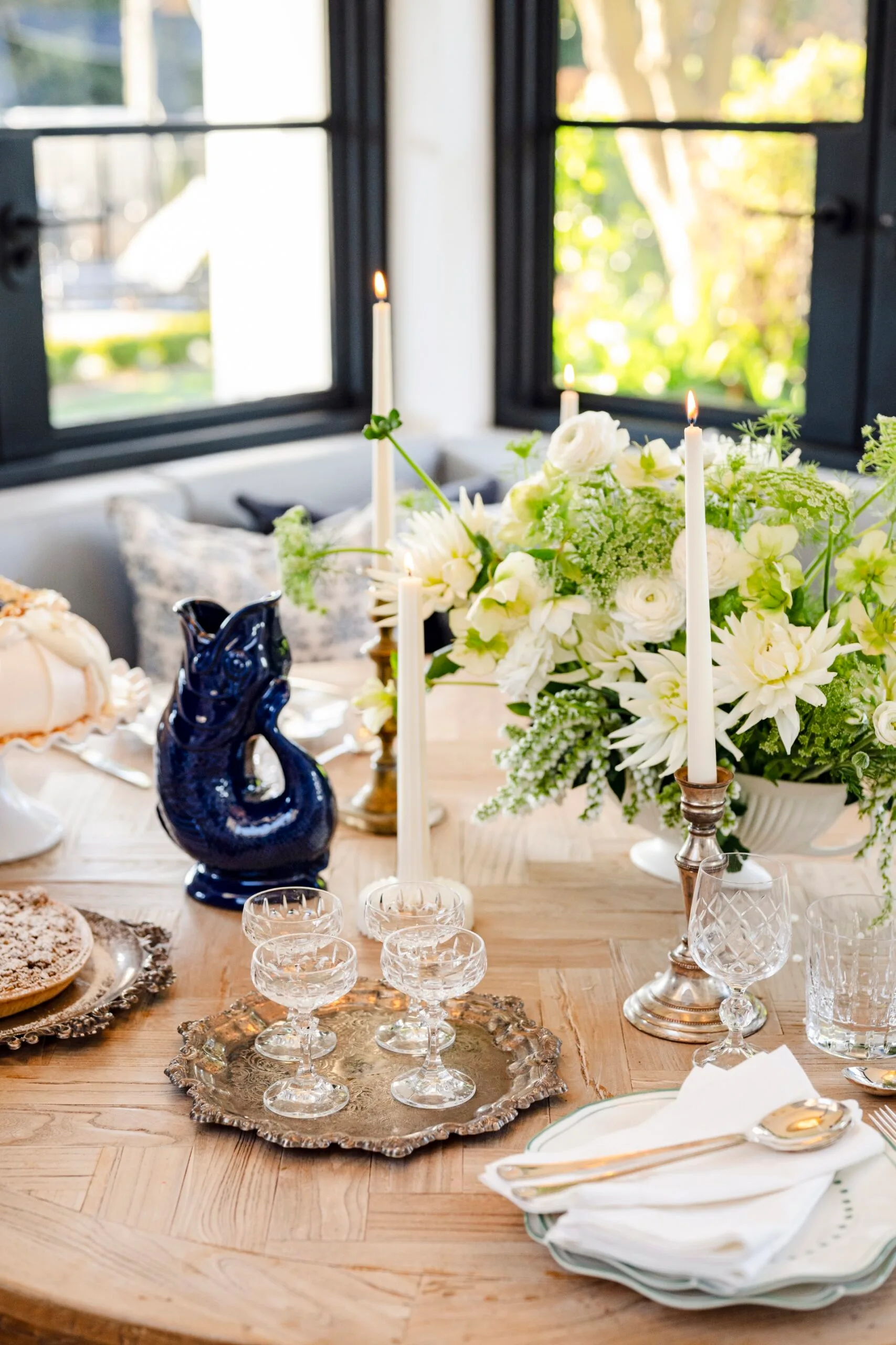 A timber table decorated with glassware and a white floral arrangement