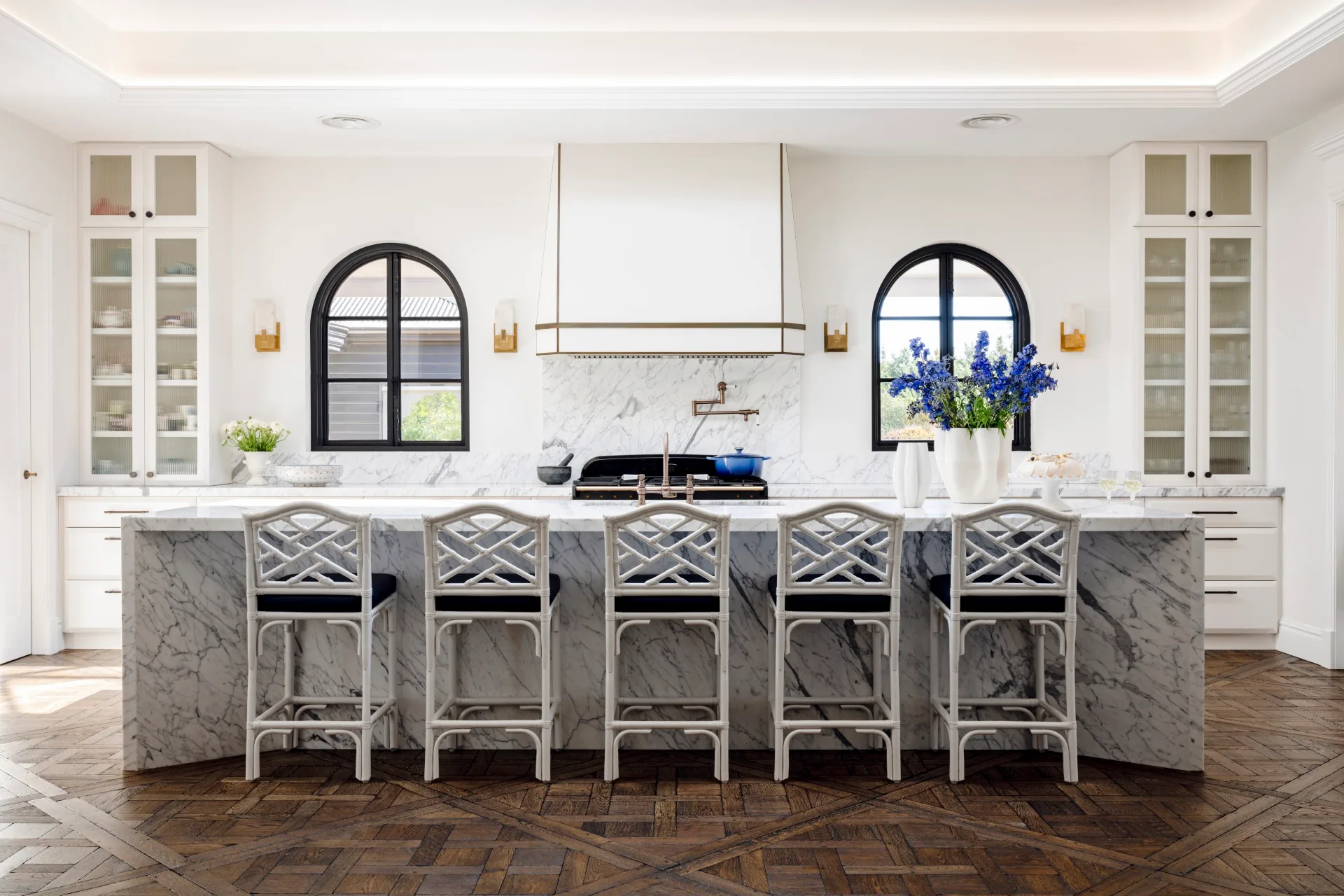 A white kitchen with a large marble island bench