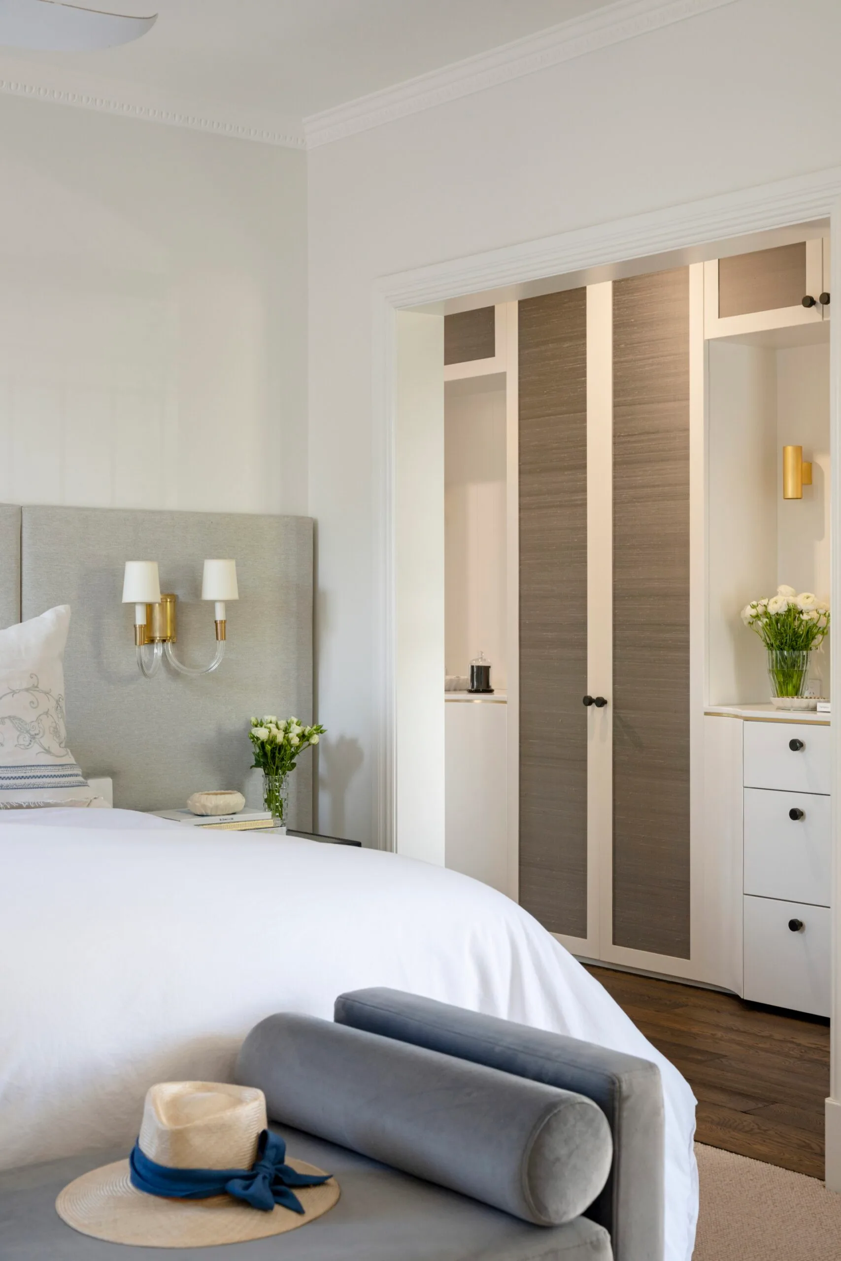 A modern country bedroom with built in cabinetry and a soft headboard
