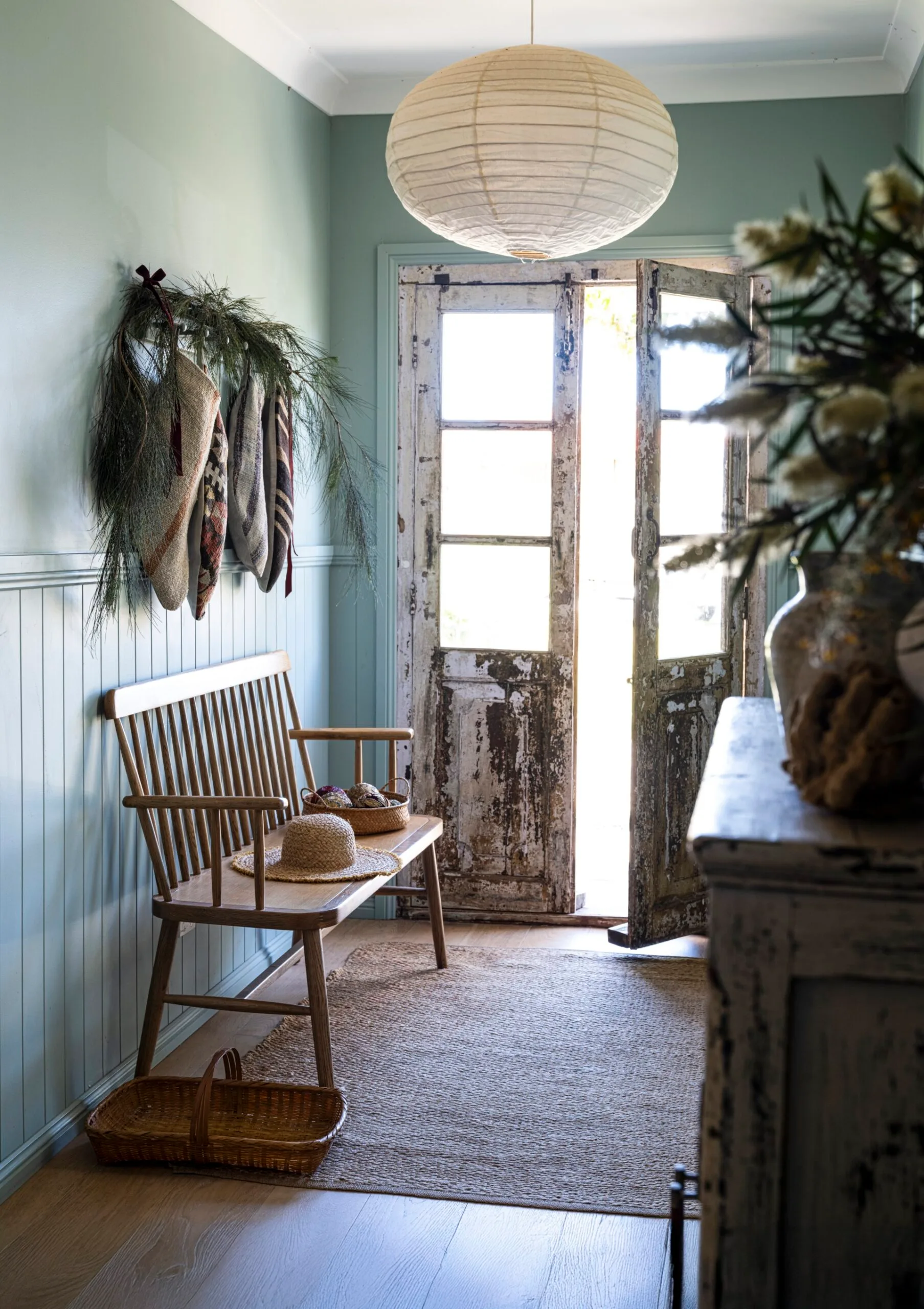 A rustic entryway features blue walls, a paper light and an bench chair