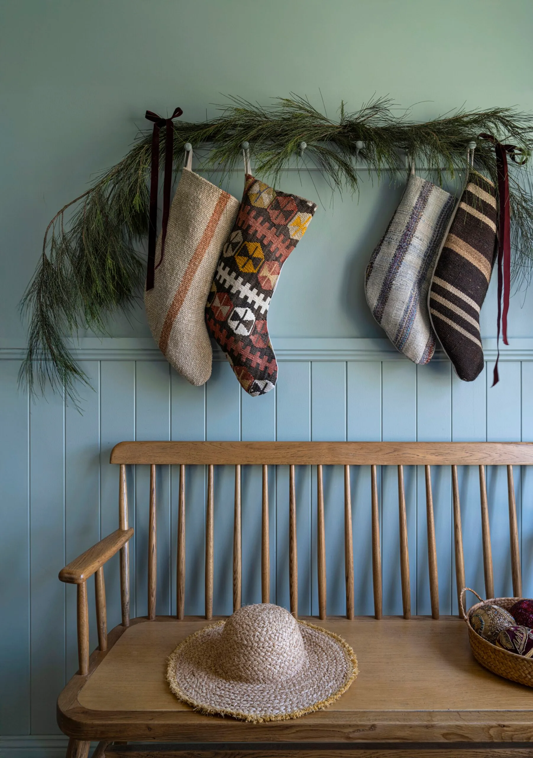 An entryway decorated with Christmas stockings and greenery.