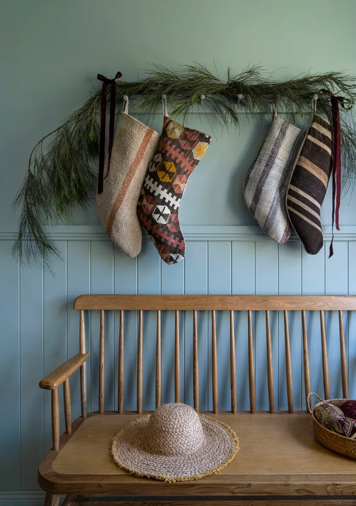 An entryway decorated with Christmas stockings and greenery.
