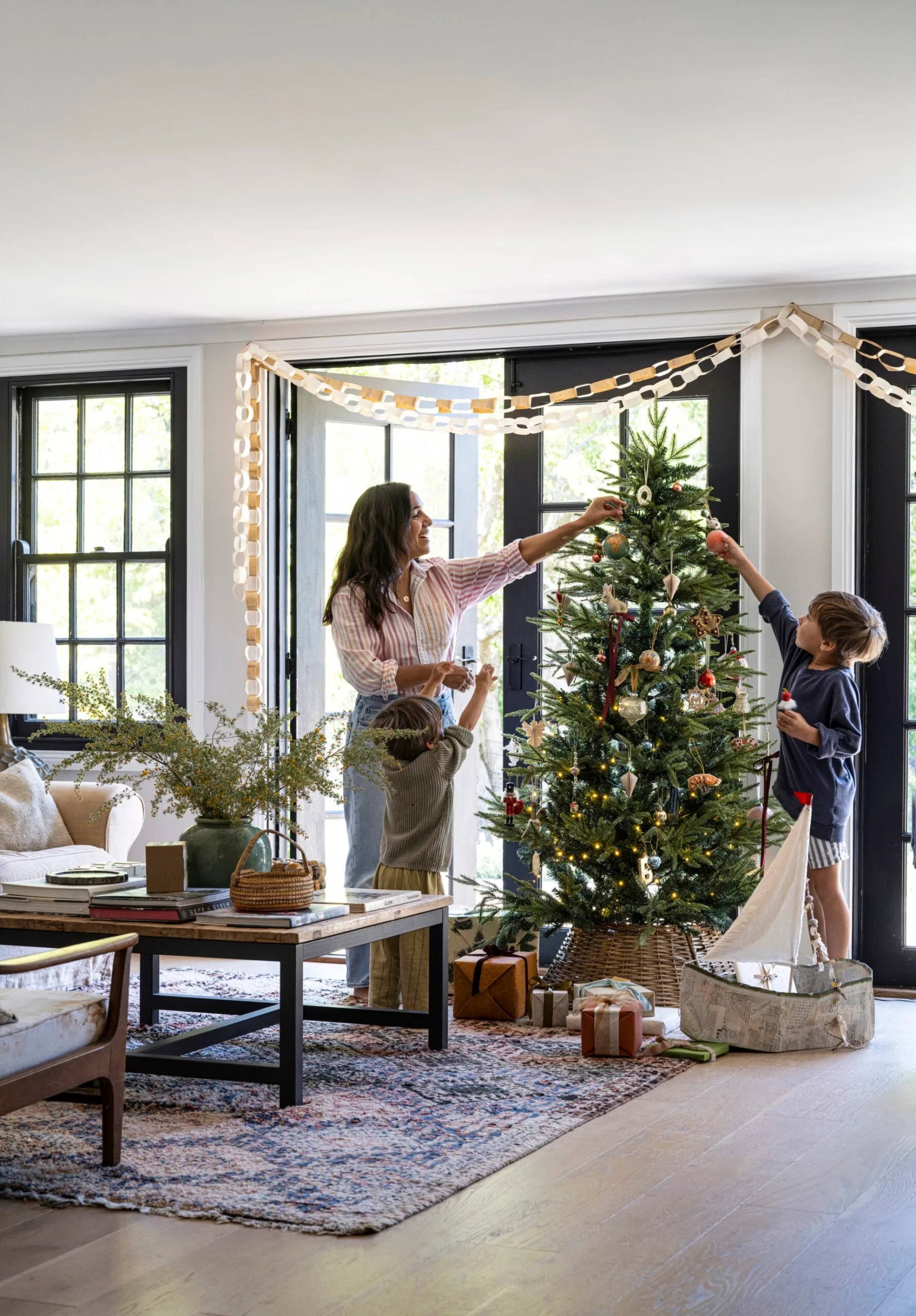 A mother and her young sons decorate a Christmas tree