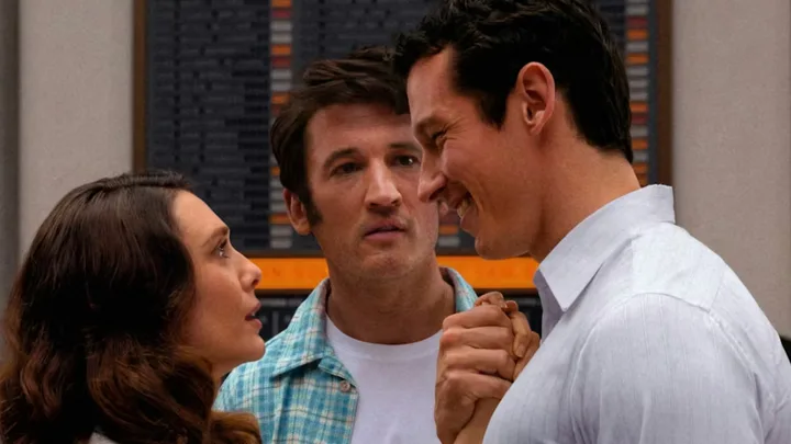 A woman and man holding hands and staring into each others eyes, with man in checked shirt behind looking at them from Eternity. Movia about the afterlife.