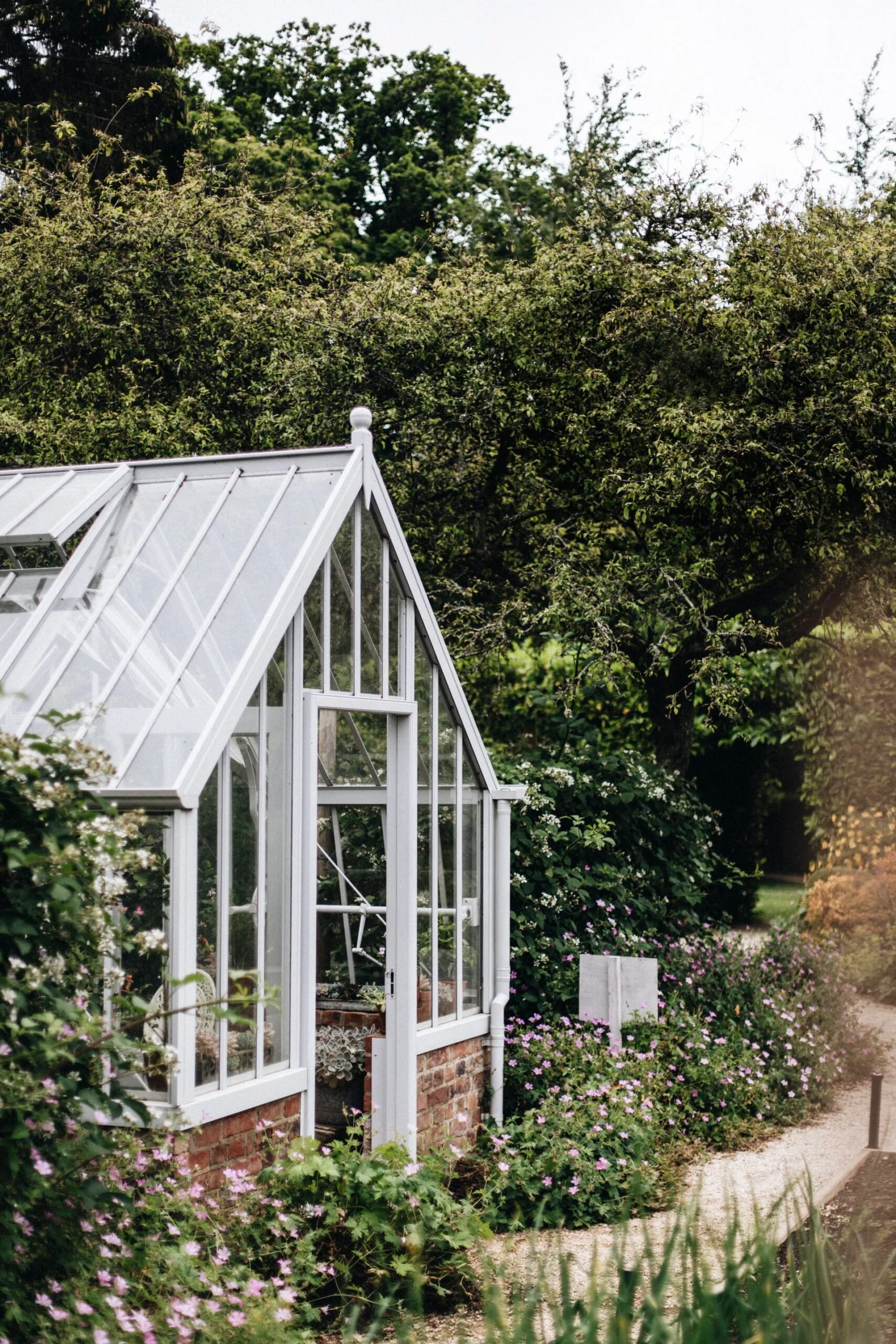 A greenhouse in a kitchen garden surrounded by trees