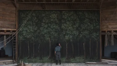 A still image of actor Paul Mescal standing in front of a landscape painting hung up on the stage of The Globe theatre, created for the Golden Globe winning film Hamnet.