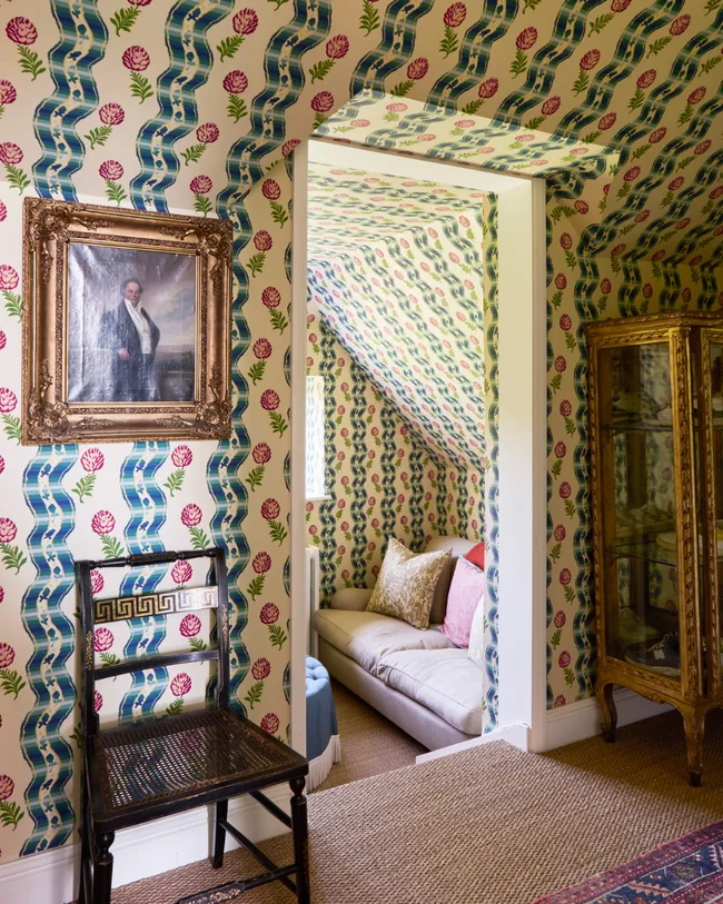 A wallpapered room with view of lounge