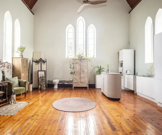 Church conversion for sale in Port Wakefield South Australia showing a light interior with contemporary white kitchen and antique furniture.