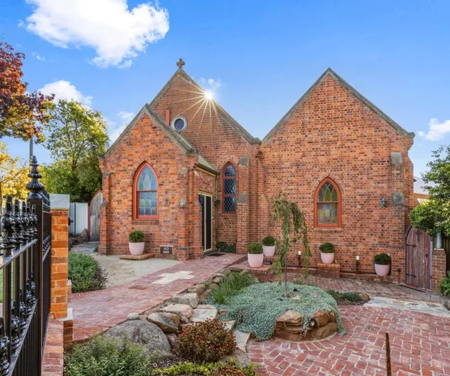 a traditional exterior of a church for sale in Junee New South Wales with stained-glass windows and manicured hedging.